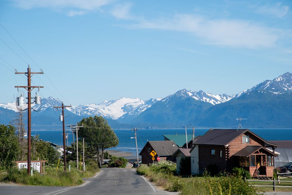 A grilled halibut fillet on a picnic table with the pewter water of Kachemak Bay and distant mountains behind