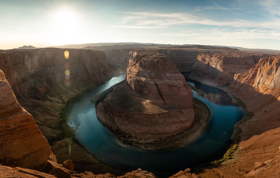 Sunrise turning the canyon walls copper and red above the emerald Colorado River