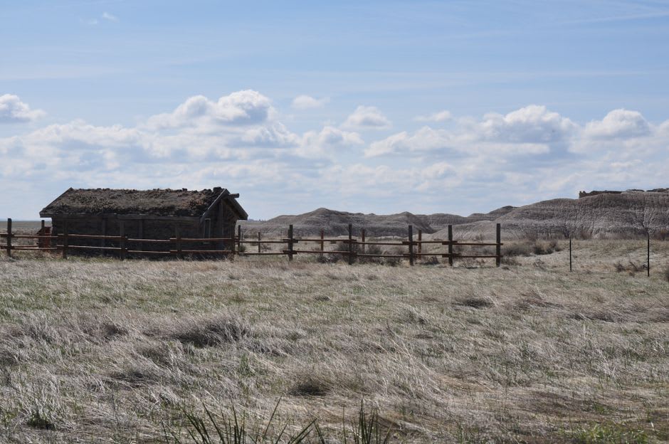 The reconstructed Ingalls family log cabin standing alone on open prairie grassland near Independence, Kansas