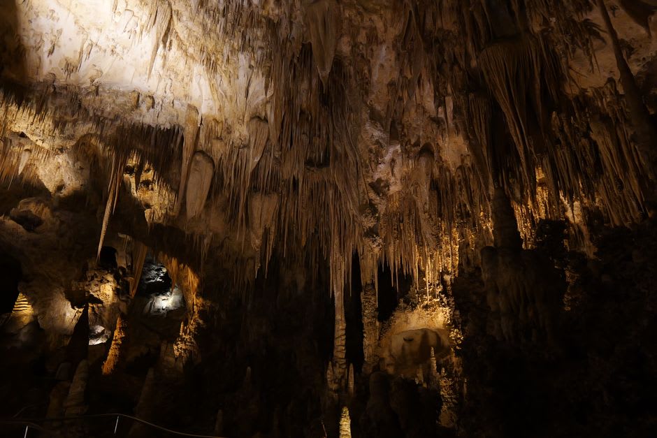 The rippled flowstone draperies of Frozen Niagara in Mammoth Cave, tinted amber and cream and lit from below