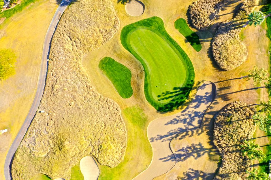 A golf course fairway with bright green grass set against red sandstone bluffs near Mesquite, Nevada