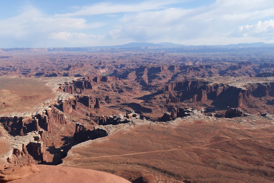 Vast canyon vista with layered mesas and buttes in Canyonlands at golden hour