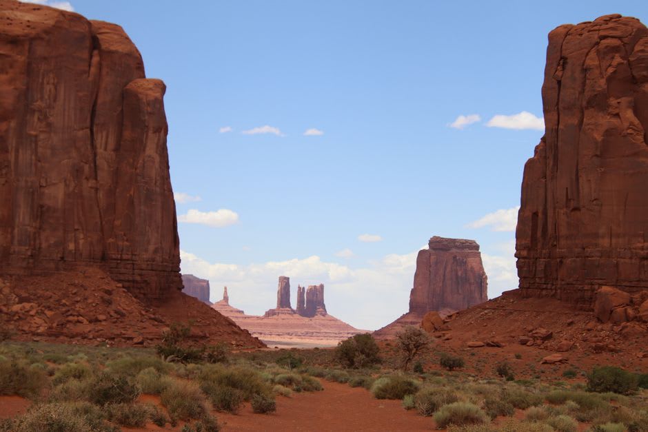 The Mittens buttes rising above the red dirt valley loop road in Monument Valley