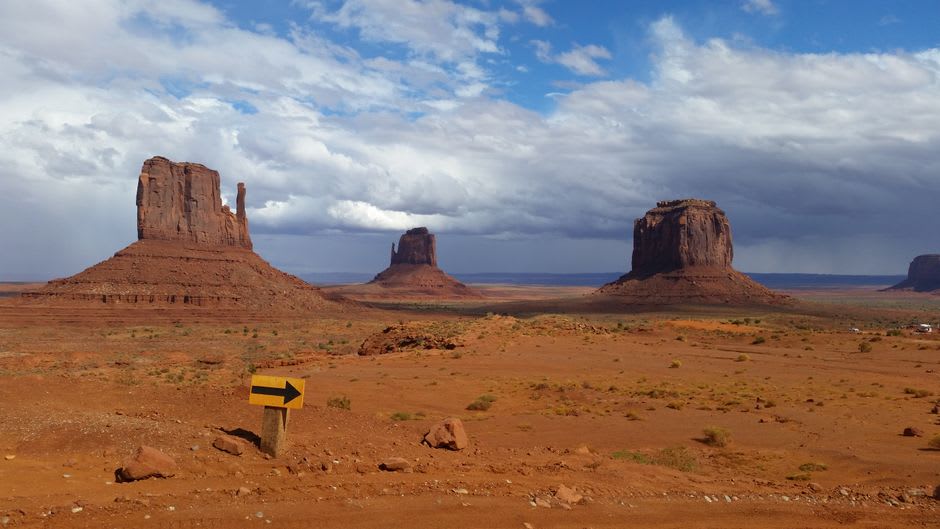 The Mittens silhouetted against a deep blue post-sunset sky in Monument Valley