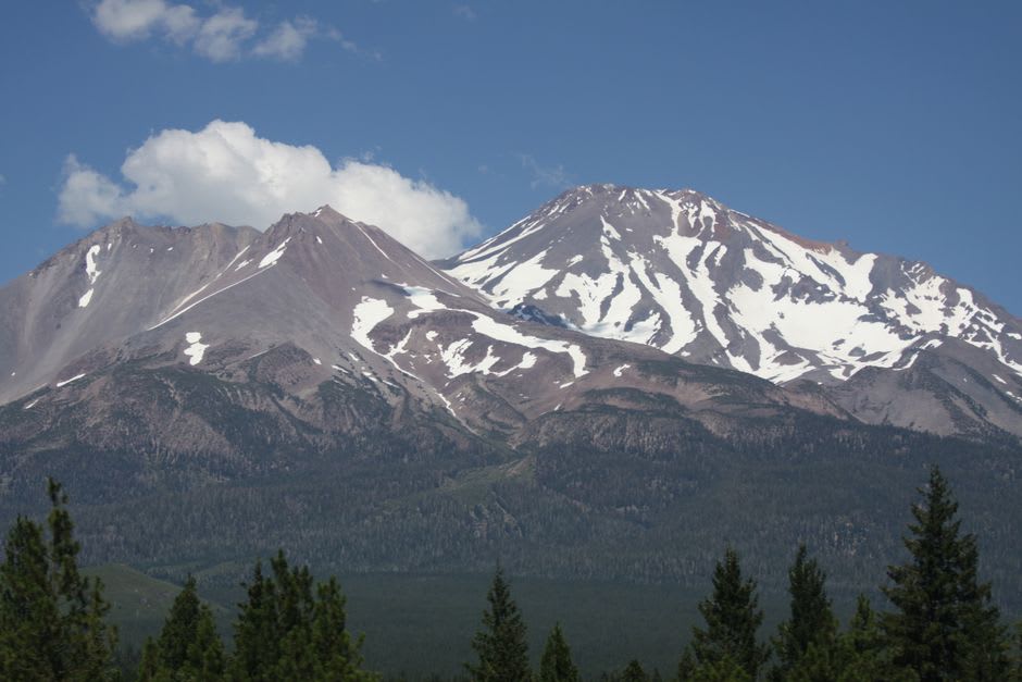 The main street of Mount Shasta City with shopfronts and the great white peak filling the view at the end of the road