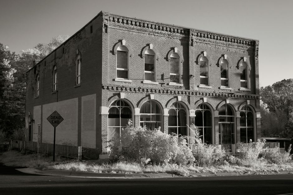 A faded historic ghost sign painted on a brick storefront along First Avenue in Mount Vernon, Iowa