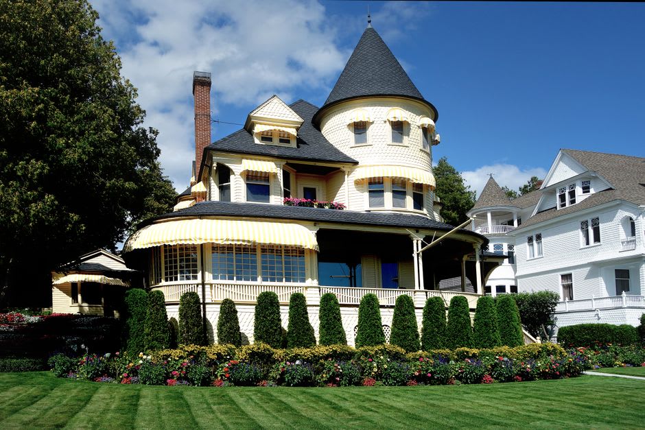 A row of restored Victorian mansions with turrets and wraparound porches on Main Street in New Albany, Indiana