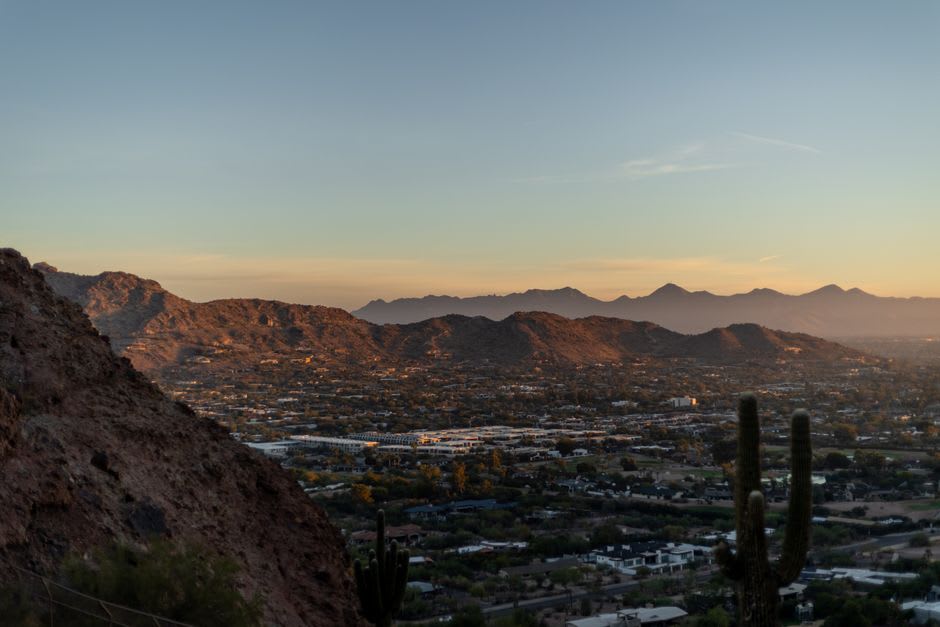 Hikers on the red rock trail up Camelback Mountain with the Phoenix valley spread out below
