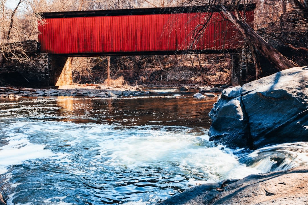 A historic covered bridge over a waterfall next to a working gristmill in Parke County near Rockville, Indiana