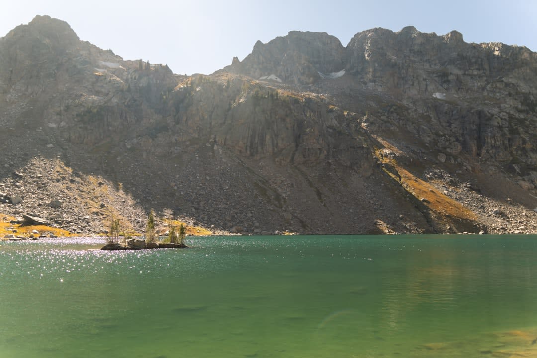 Emerald Lake sitting in a granite cirque with lingering snow beneath sheer peaks