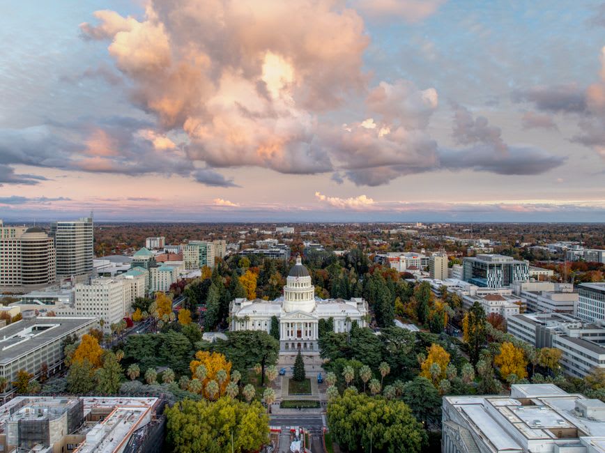 The white dome of the California State Capitol above its tree-filled park