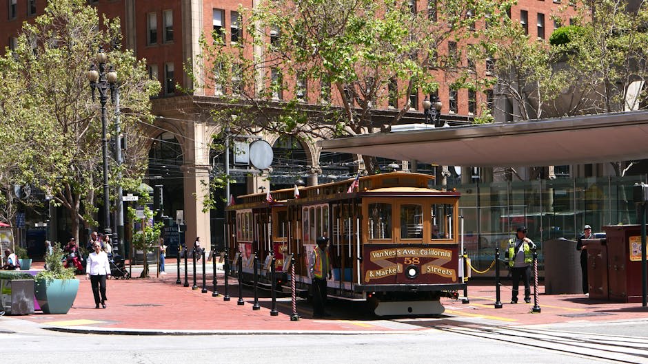 A classic San Francisco cable car climbing a steep hill with the bay in the distance