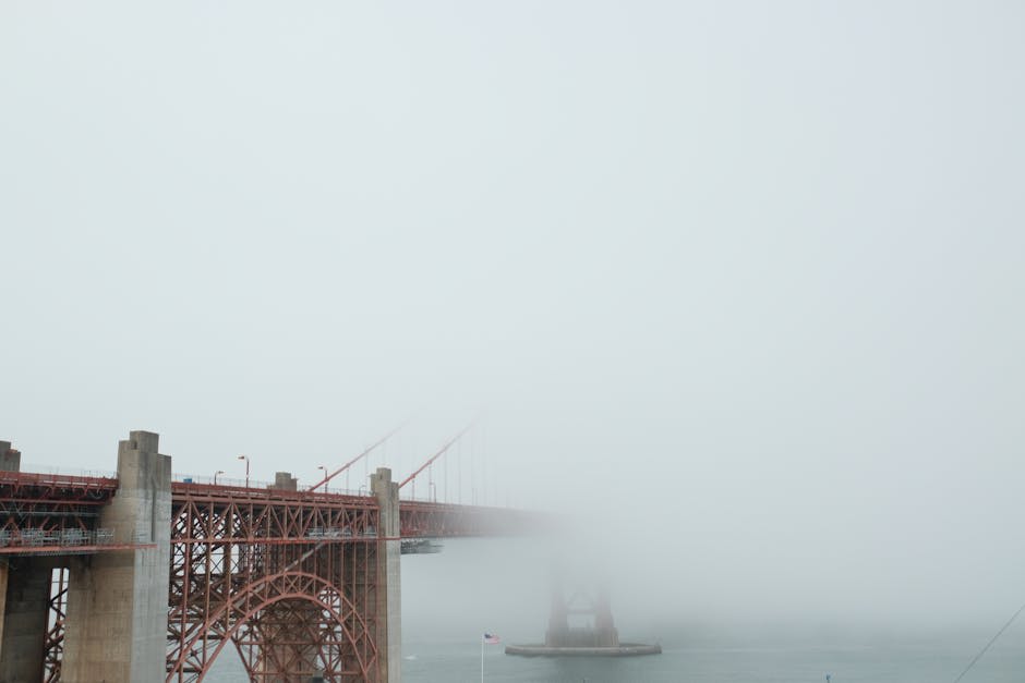 The Golden Gate Bridge partially veiled in morning fog over the bay