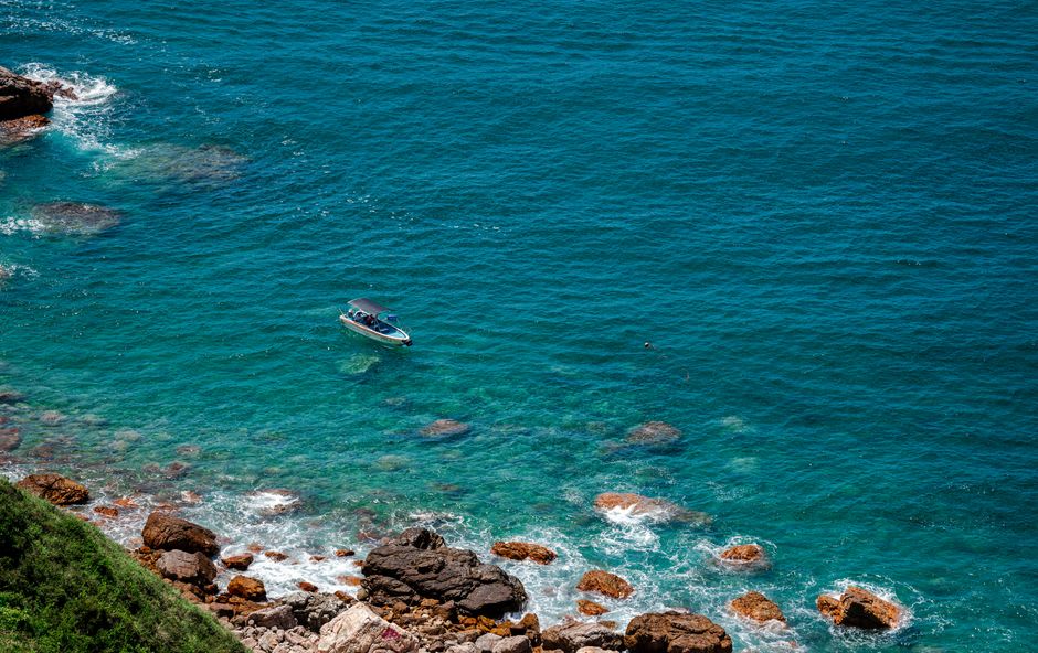 A pontoon boat anchored in a clear turquoise cove surrounded by sandstone bluffs on Lake Cumberland near Somerset, Kentucky