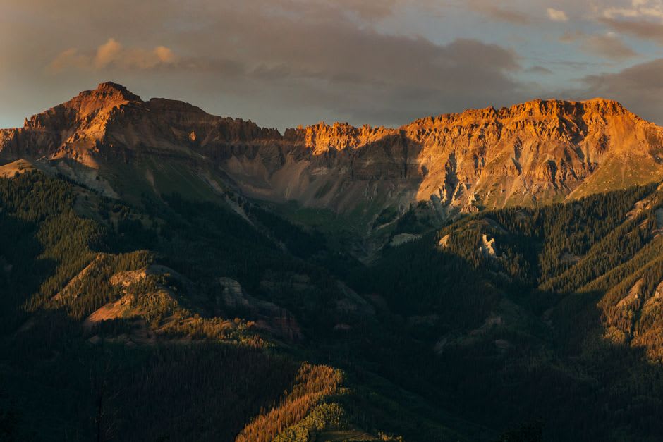 Telluride's free gondola cabin rising over the pine ridge between the town and Mountain Village