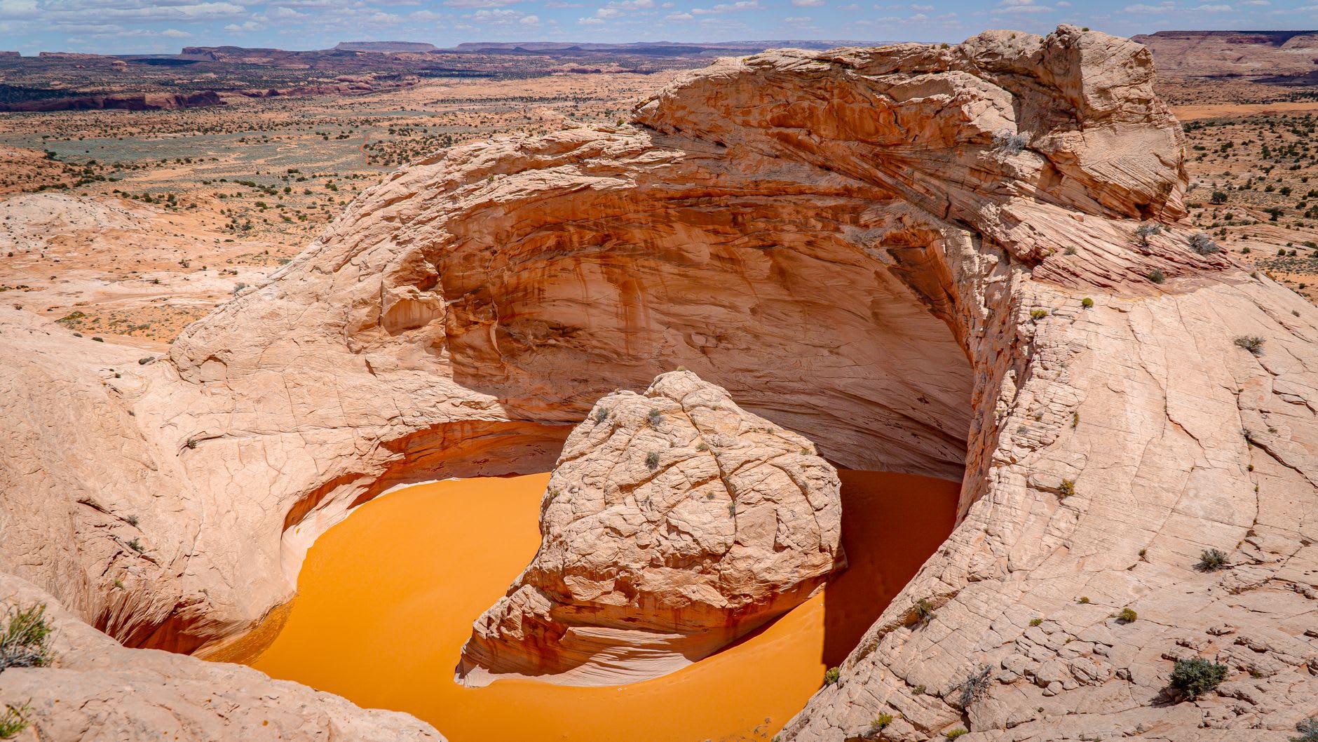A wide desert basin with stepped layers of coloured cliffs rising in the distance