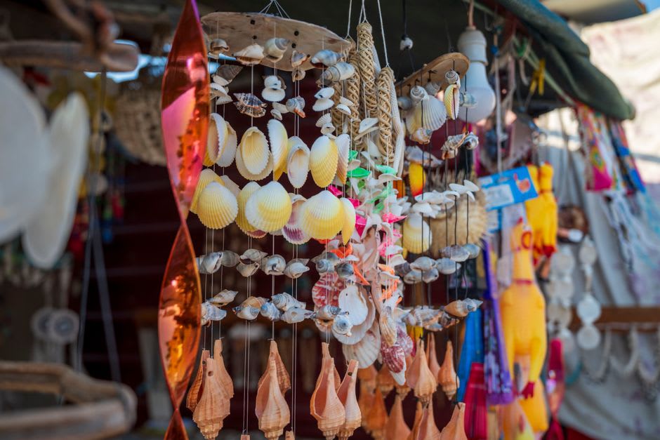Local stalls selling handicrafts and grilled food near the tree line at Champagne Beach