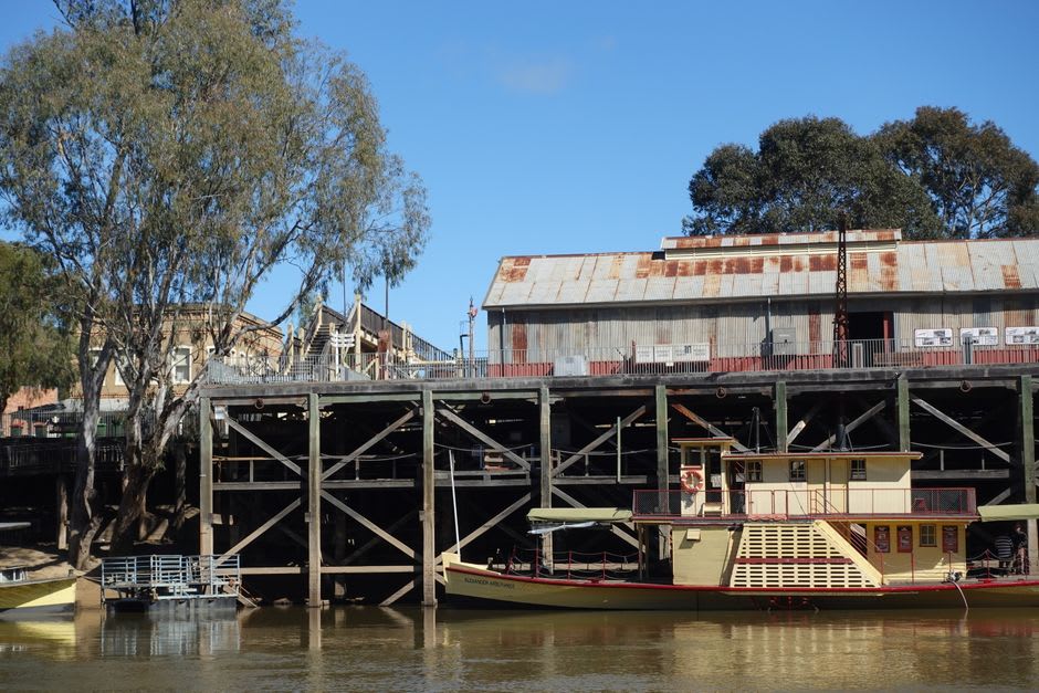 El muelle de madera de eucalipto rojo de varios niveles en Echuca, con cobertizos de carga y un barco de vapor amarrado al costado