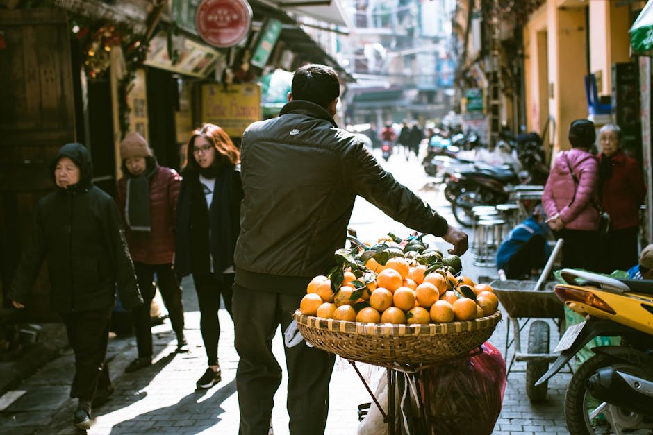 A busy street scene in Hanoi with a vendor selling fresh oranges