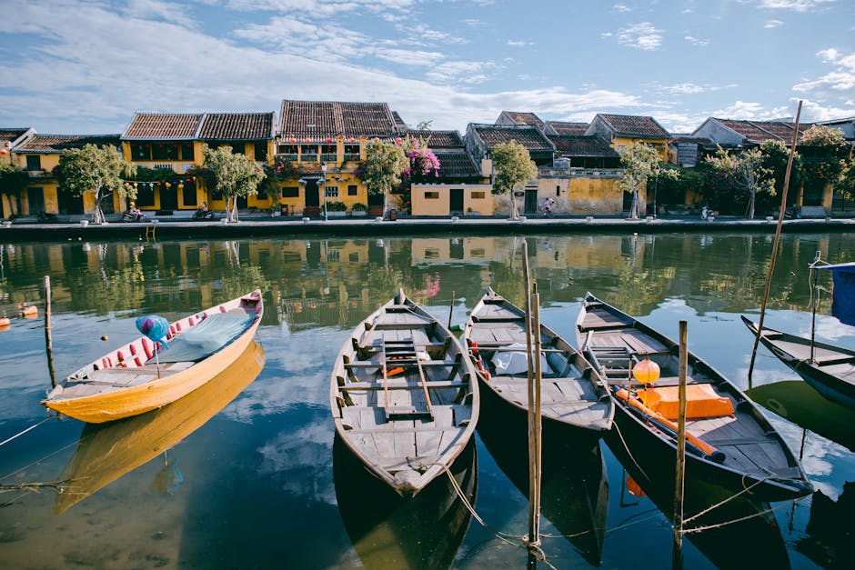Traditional boats on a calm river reflecting yellow historic buildings in Hoi An