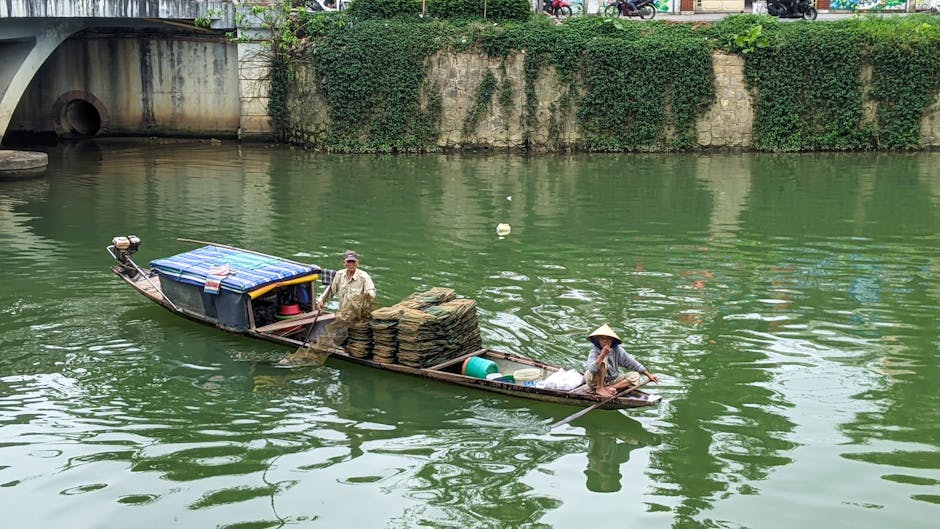 Two people navigating a traditional boat on the Perfume River in Hue