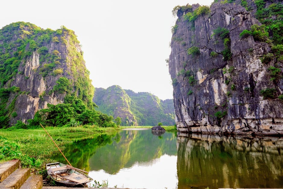 Ninh Binh's limestone cliffs and serene water reflection with a traditional rowboat