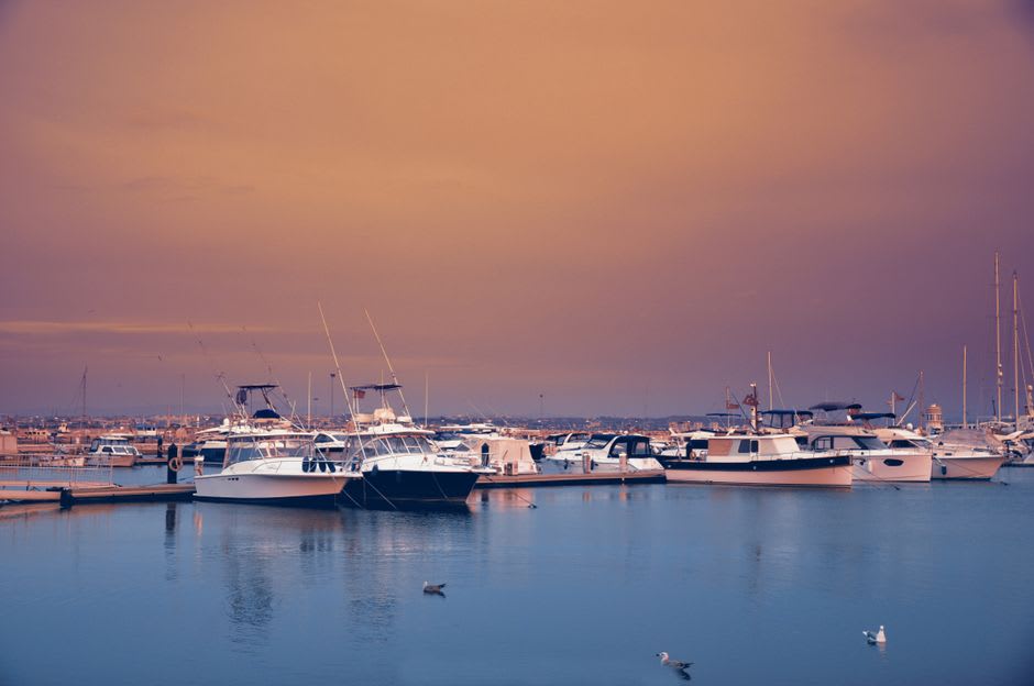 Fishing boats moored in Lancelin's harbour at sunset with the coastline in the background