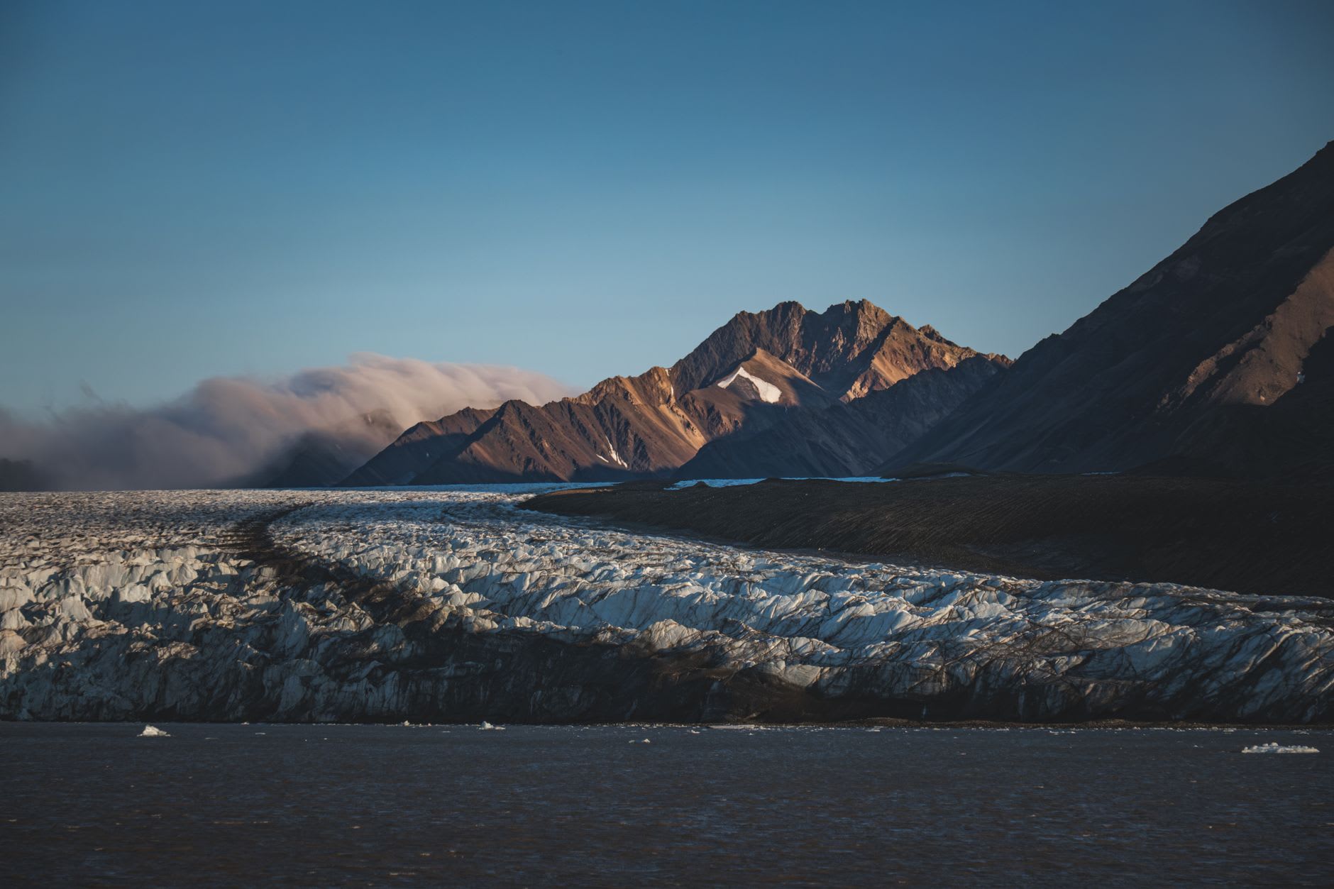 Weathered wooden whaling-era buildings standing on flat Arctic tundra near the shore