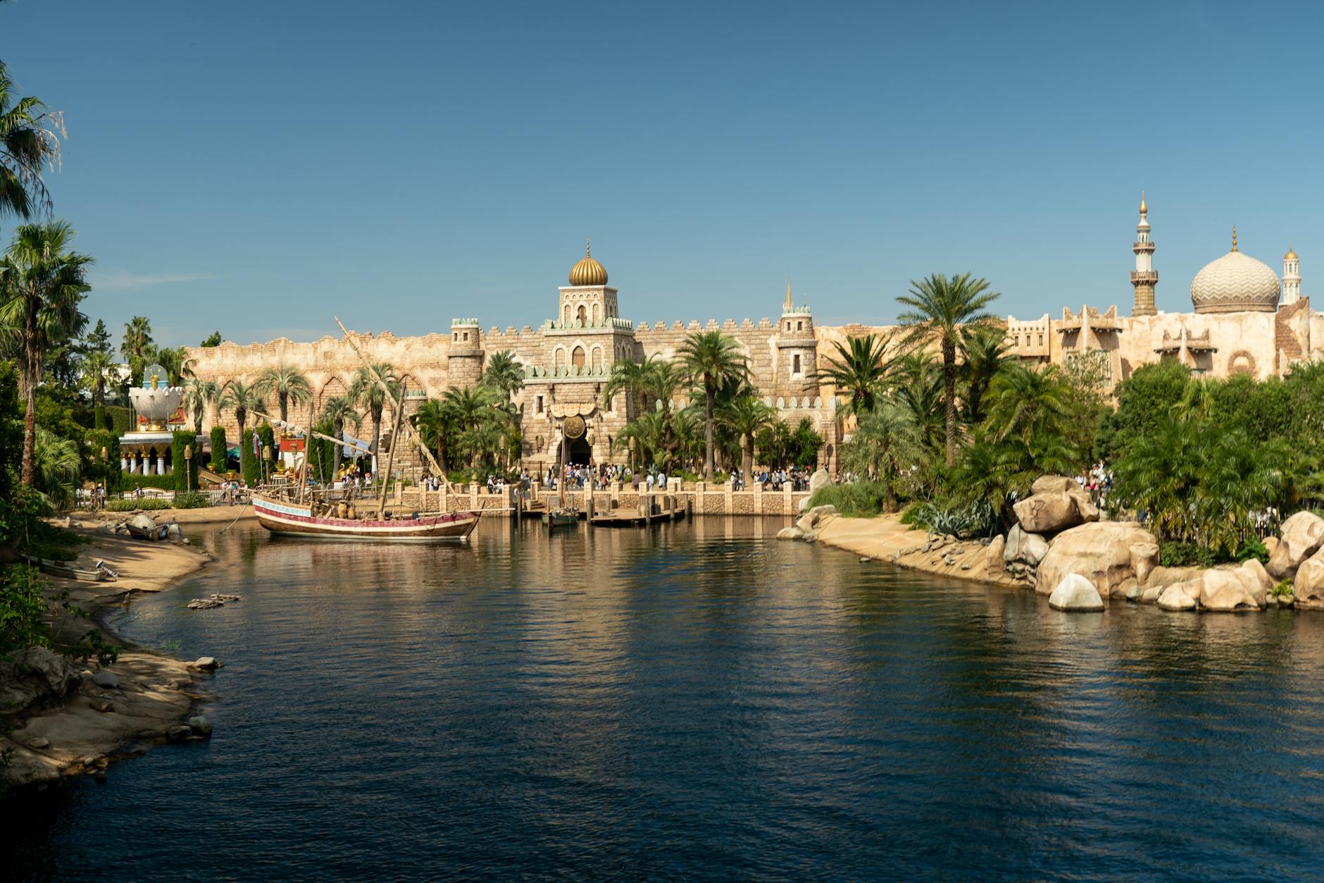 Theme park harbor with ornate buildings and boats on calm water