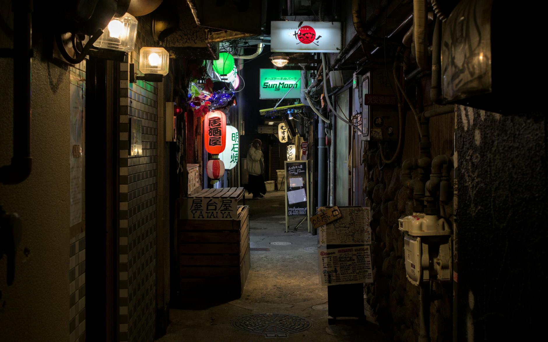 Warm glow of an Osaka street food alley at night with lanterns and small restaurants