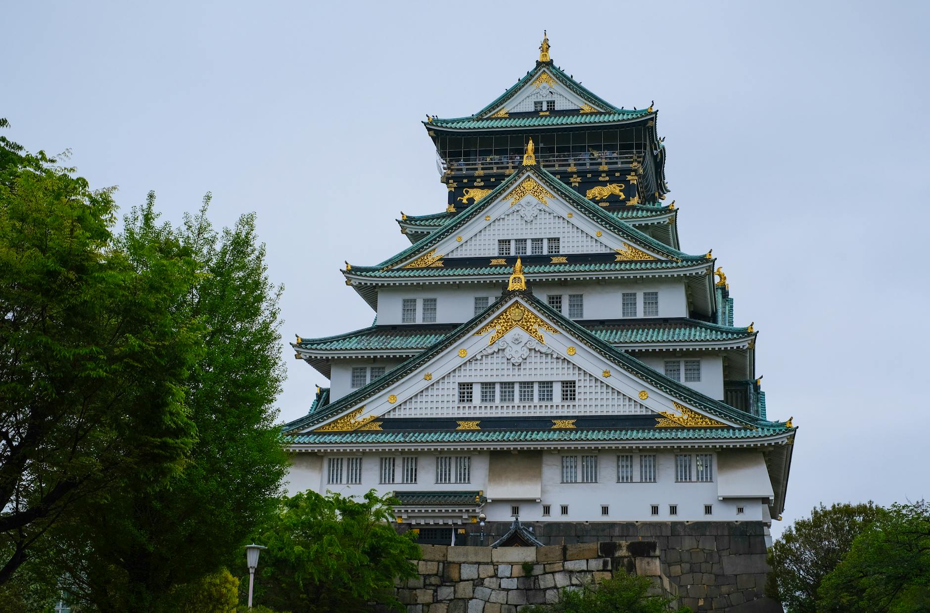 Osaka Castle with its white walls and green-gold roof surrounded by stone walls and moat