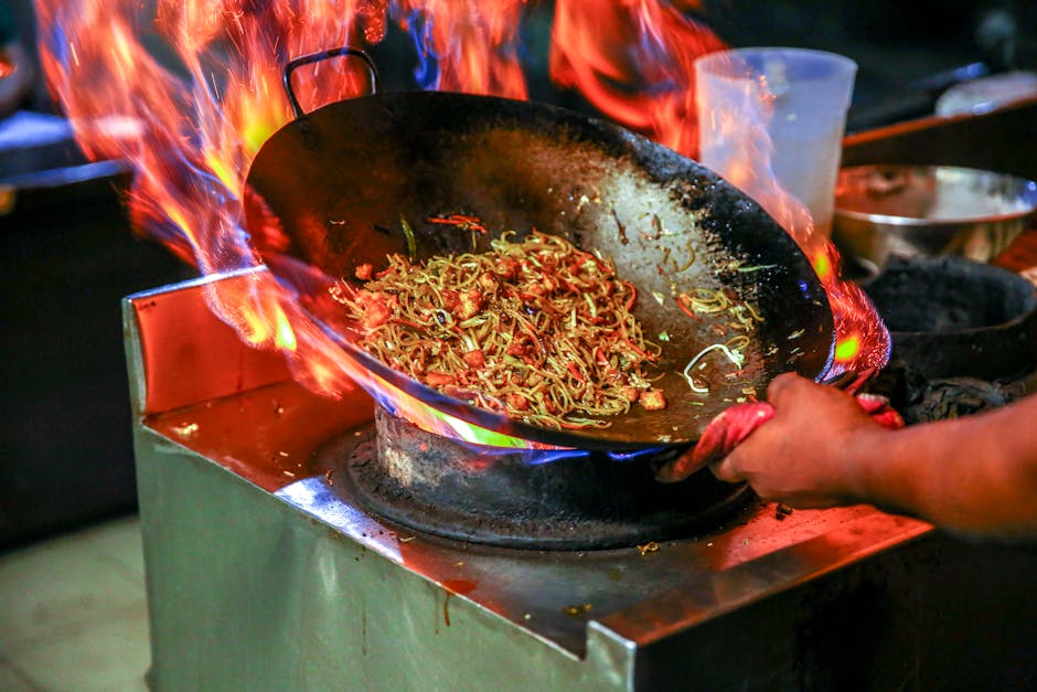 A plate of char kway teow being fried over charcoal at a George Town hawker stall