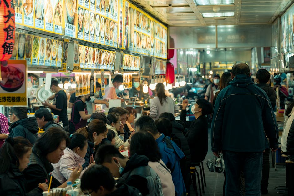 Hawker centre tables crowded with bowls of noodle soup and plates of local dishes