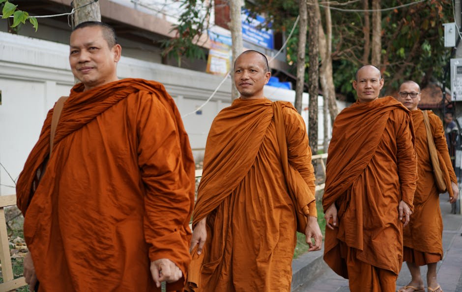 Monks in saffron robes walking through a sunlit Chiang Mai temple courtyard
