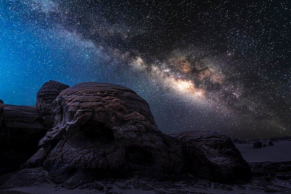 The Milky Way stretching across a dark desert sky above silhouetted mesas