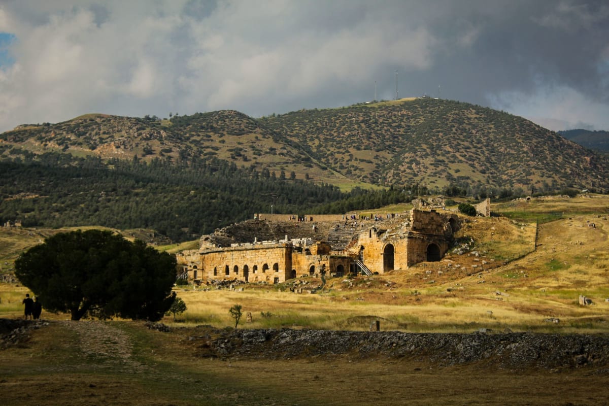 The colonnaded main street of Timgad with intact Roman columns lining the way toward the Trajan Arch against the Aurès mountain sky