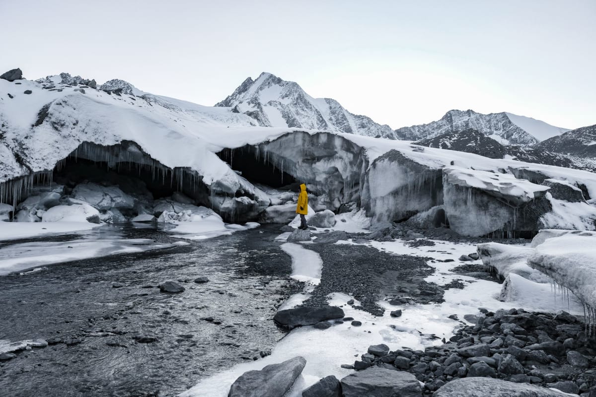 La rivière Aktru laiteuse coulant dans la vallée depuis le glacier avec des pentes de pierriers sombres des deux côtés