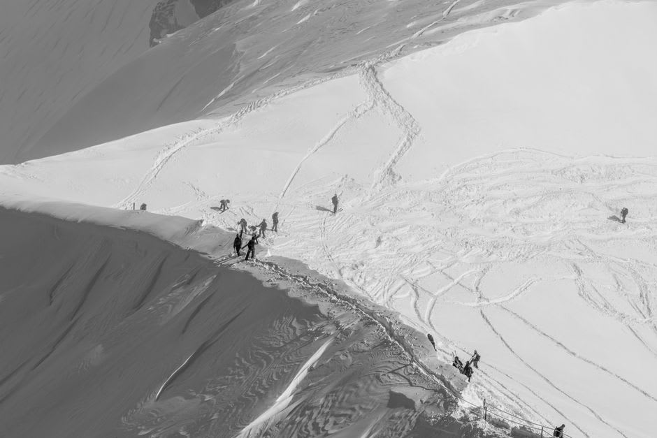Skier making fresh tracks in untouched powder snow beneath a rock ridge