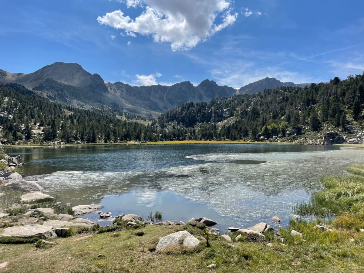 The Pessons lakes above Encamp in summer — turquoise glacial tarns in a granite cirque with Pyrenean peaks reflected in the still water