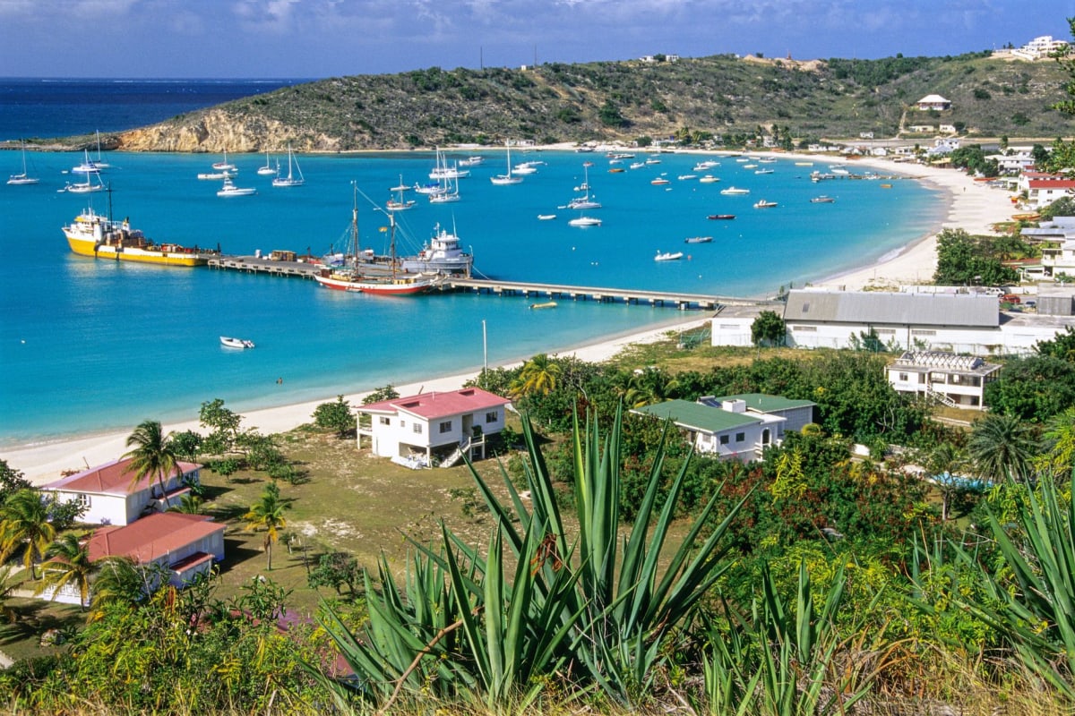 Vue le long de la plage de Dickenson Bay dans la lumière du matin, sable pâle et eau turquoise, parasols du resort au loin