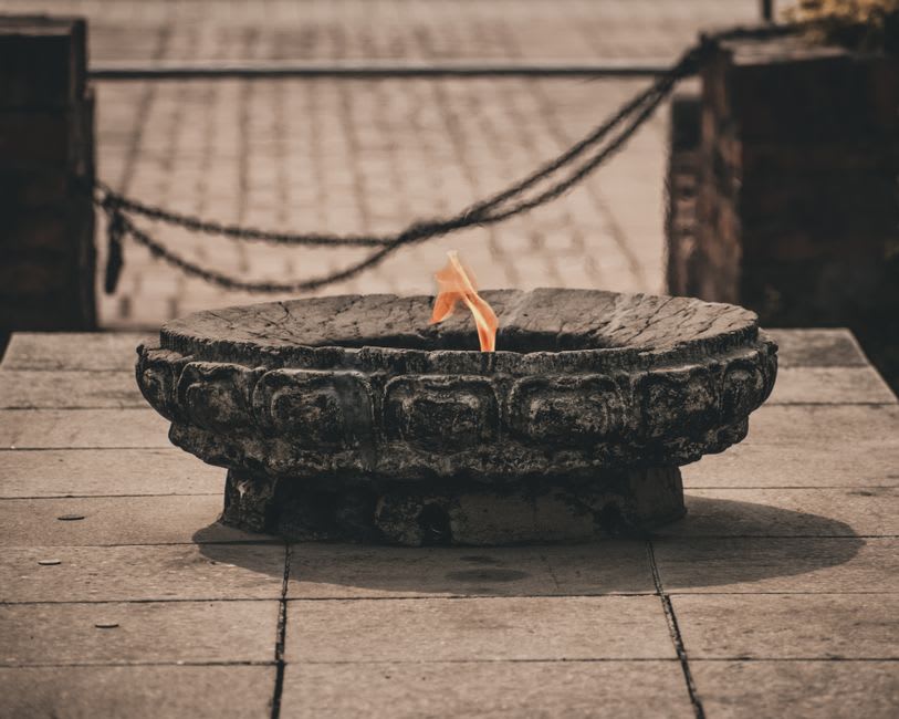 Close-up of the central altar's flame burning against the temple's sandstone arches at dusk