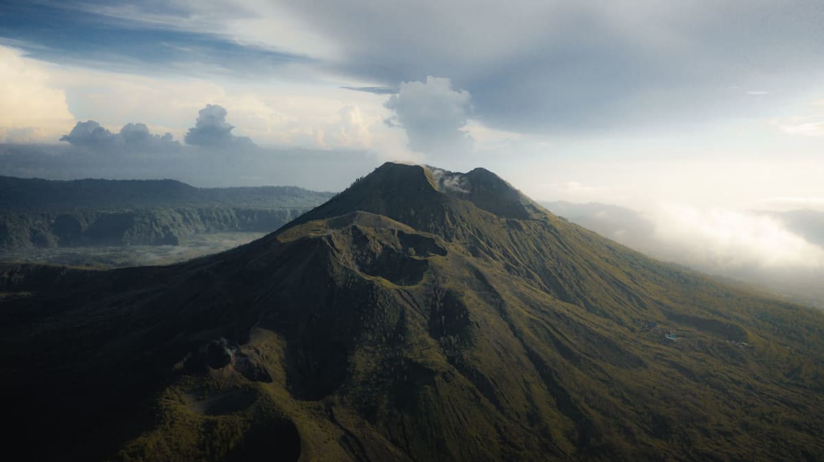 Randonneurs s'approchant du sommet du mont Batur dans l'obscurité avant l'aube avec des lampes frontales éclairant le sentier volcanique