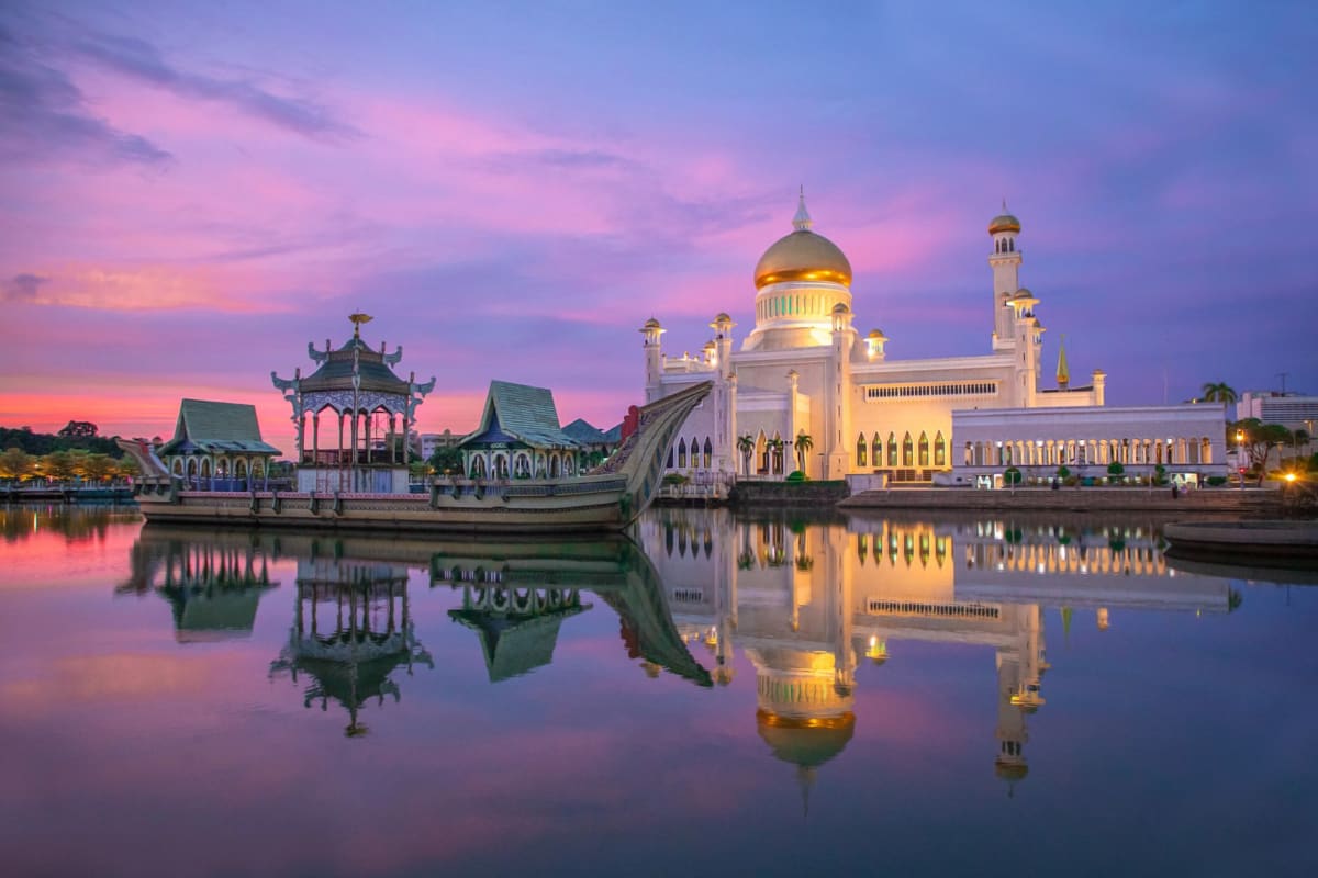 Colourful Kuching shophouses lining the waterfront on a hazy morning with the Sarawak River in the foreground