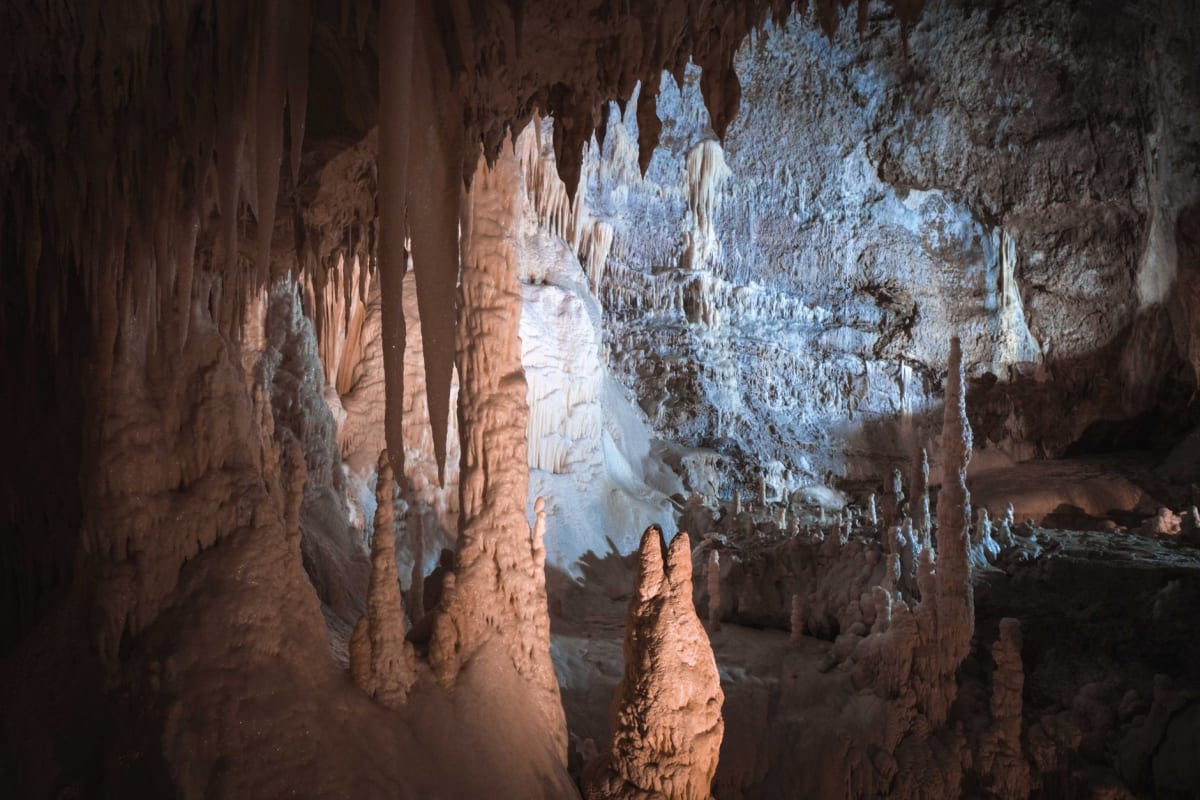 Guía penan conduciendo a visitantes por la pasarela de madera entre entradas de cuevas en la selva primaria de Mulu
