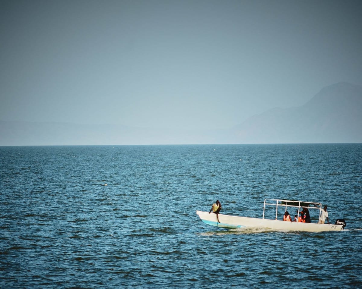 Afternoon swimmers in the still southern waters of Lake Tanganyika at Nyanza-Lac, the water gold and glassy in the late light
