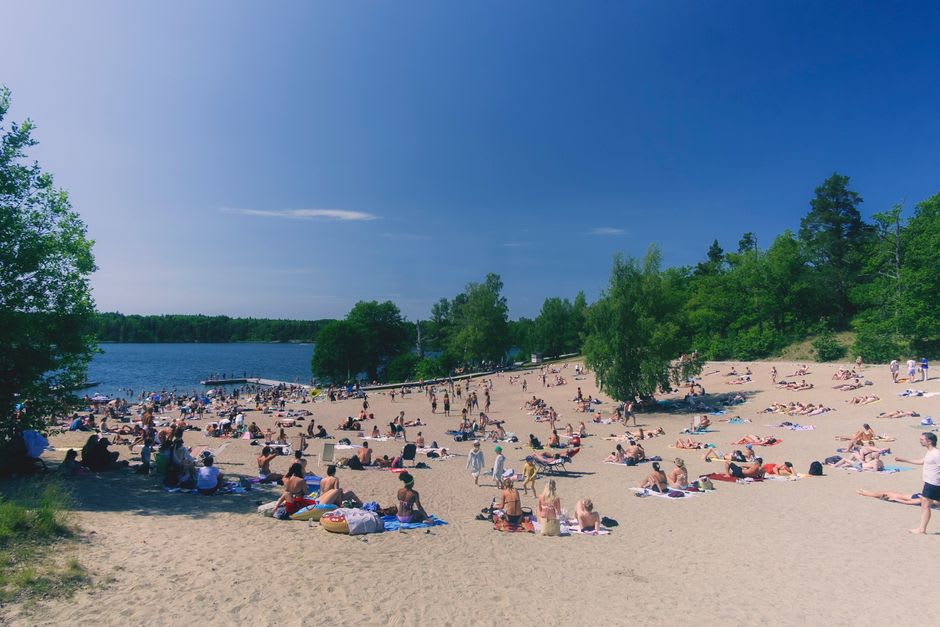 Crowded sandy beach on Lake Winnipeg at Gimli with families swimming on a summer afternoon