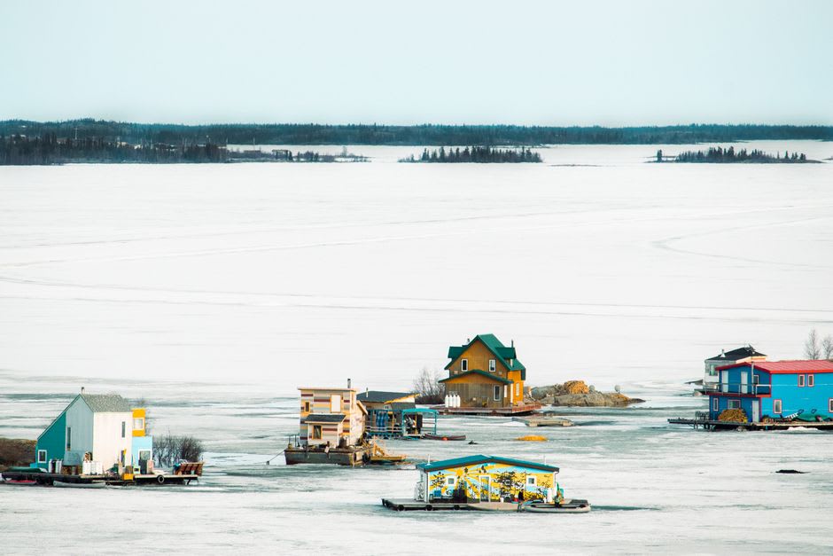Houseboats frozen into the ice of Yellowknife Bay in winter with the Old Town skyline behind