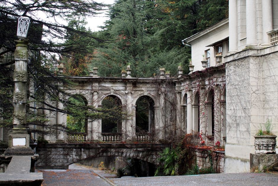 Weathered Soviet-era sanatorium building with columns set among tall pine trees