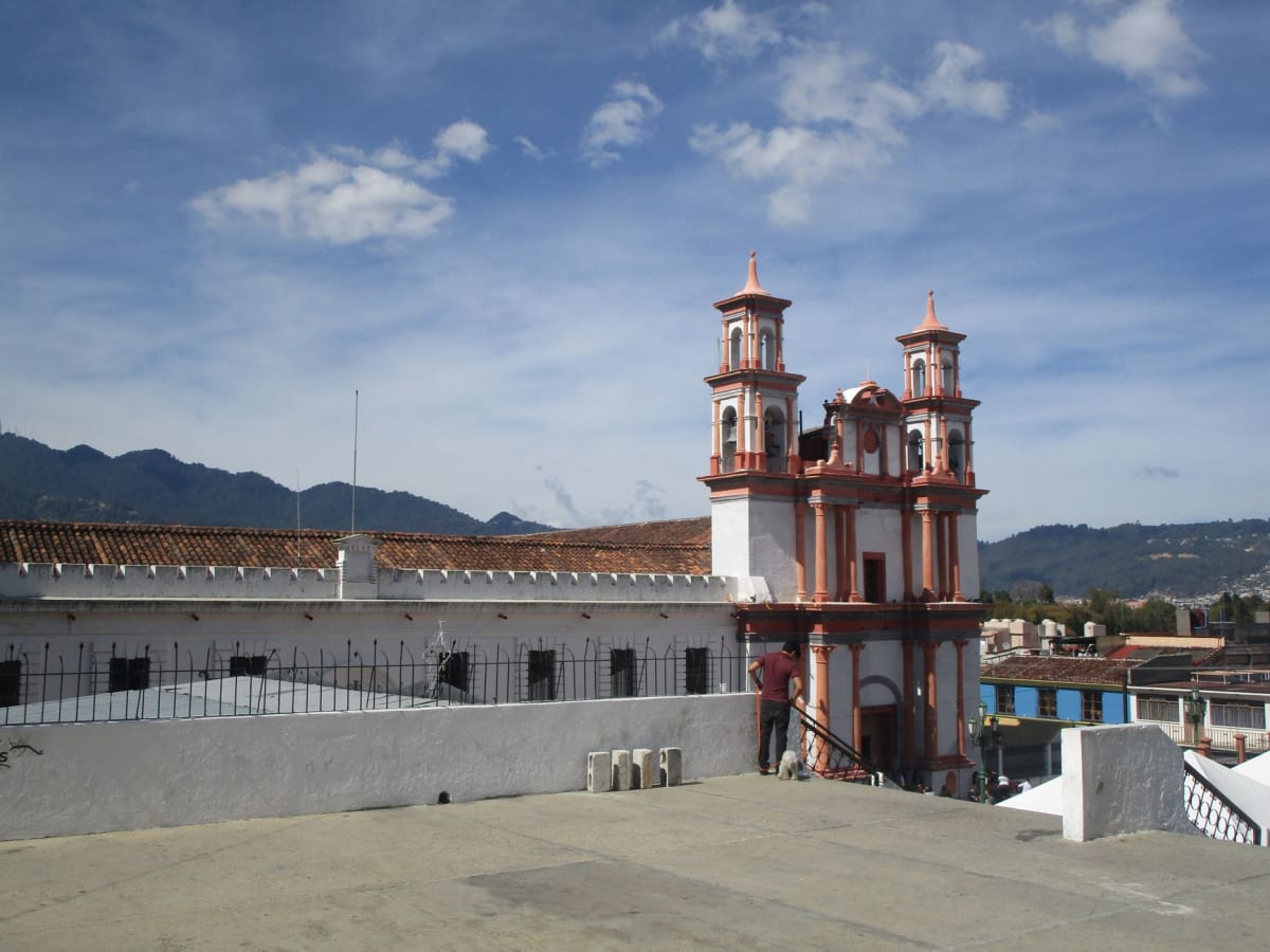 Tejido en telar de cintura en un umbral de Zinacantán, vivos patrones de hilo rosa y magenta tomando forma