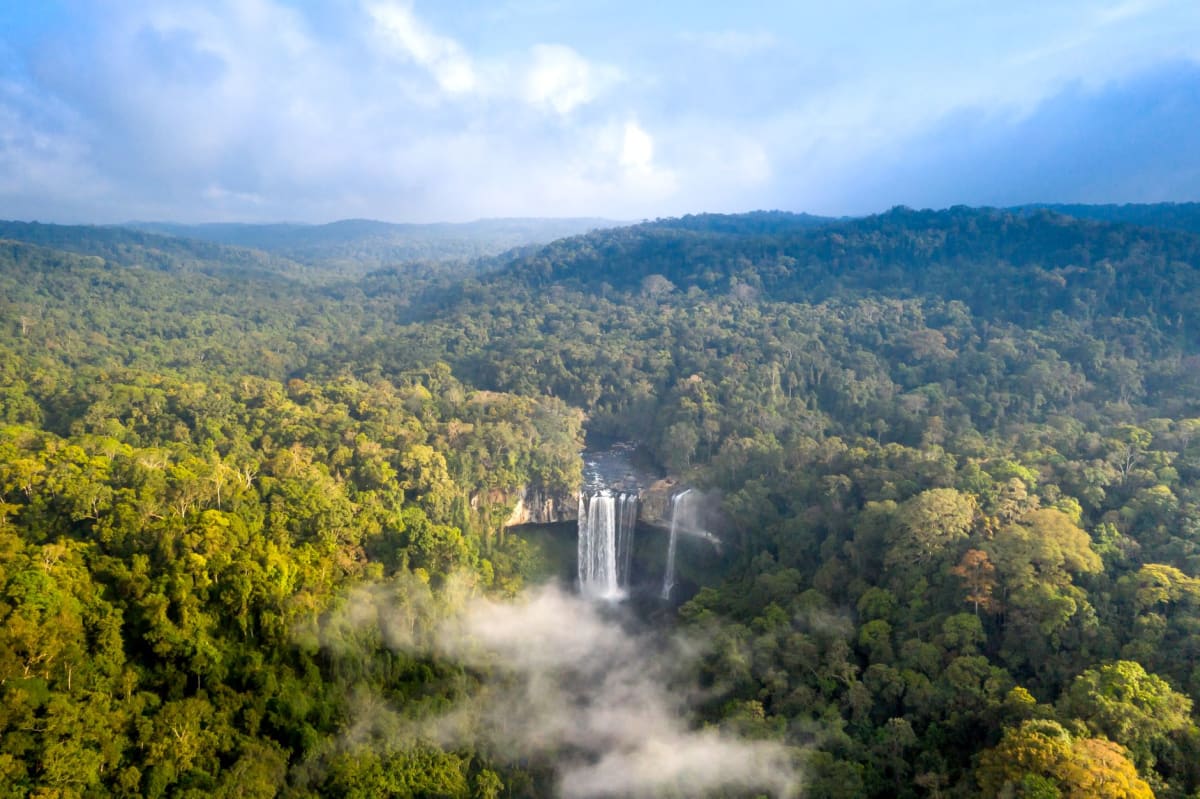 La rivière Loufoulakari teintée de rouge se déversant dans les vasques inférieures, entourée de dense jungle riveraine